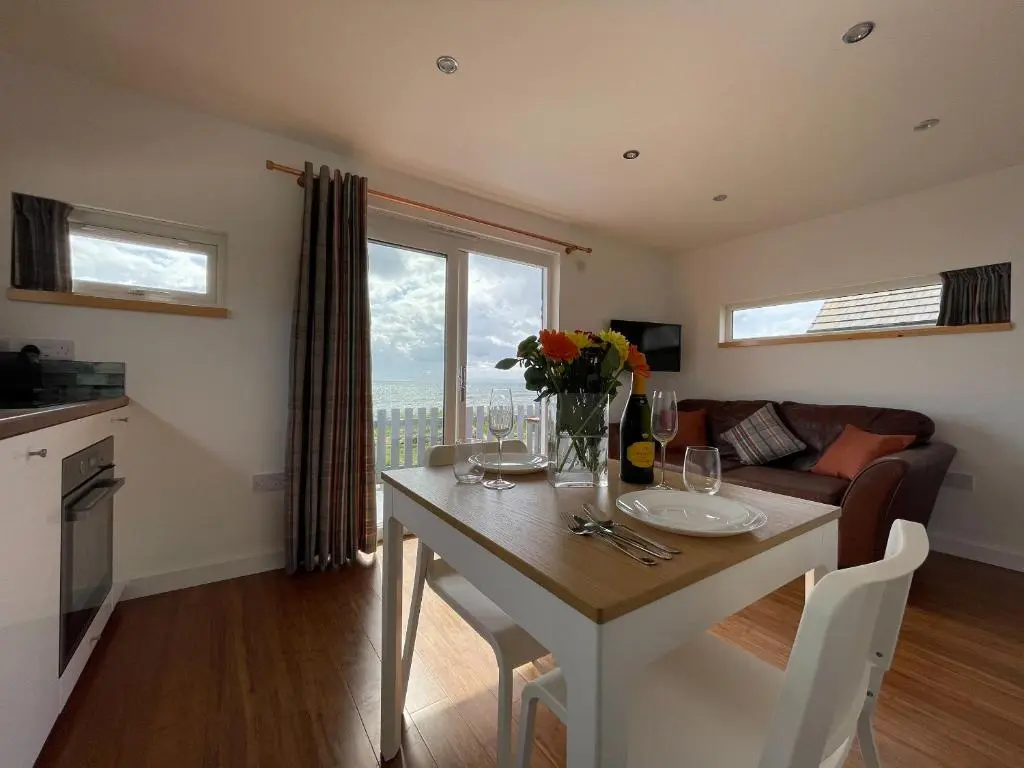 a kitchen and living room with a table with flowers on it at Sunrise Summerhouse in Hilton of Cadboll
