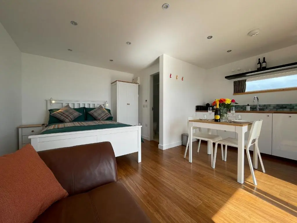a bedroom with a bed and a table and a kitchen at Sunrise Summerhouse in Hilton of Cadboll