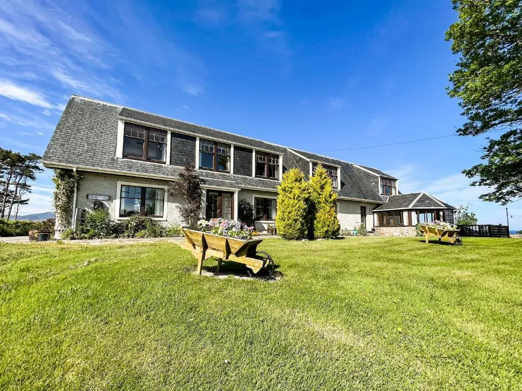 a large house with a bench in the yard at Fourpenny Cottage - Uk34744 in Embo