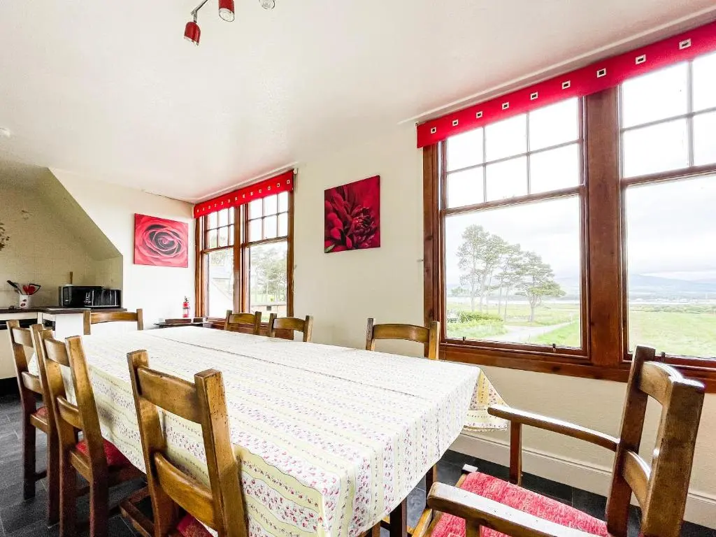 a dining room with a table and chairs and windows at Fourpenny Cottage - Uk34744 in Embo