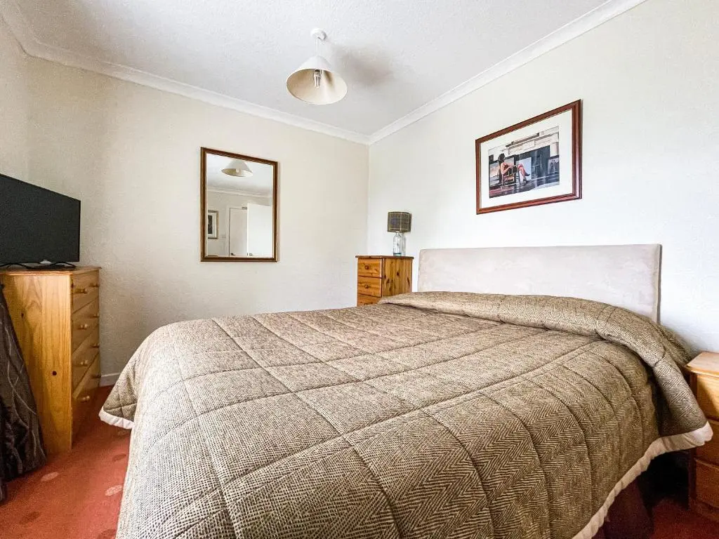 a bedroom with a bed and a flat screen tv at Fourpenny Cottage - Uk34744 in Embo