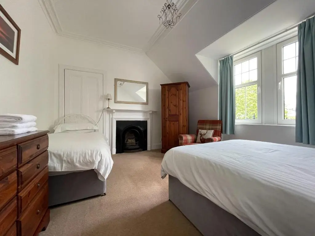 a bedroom with two beds and a fireplace at Stanford House in Inverness