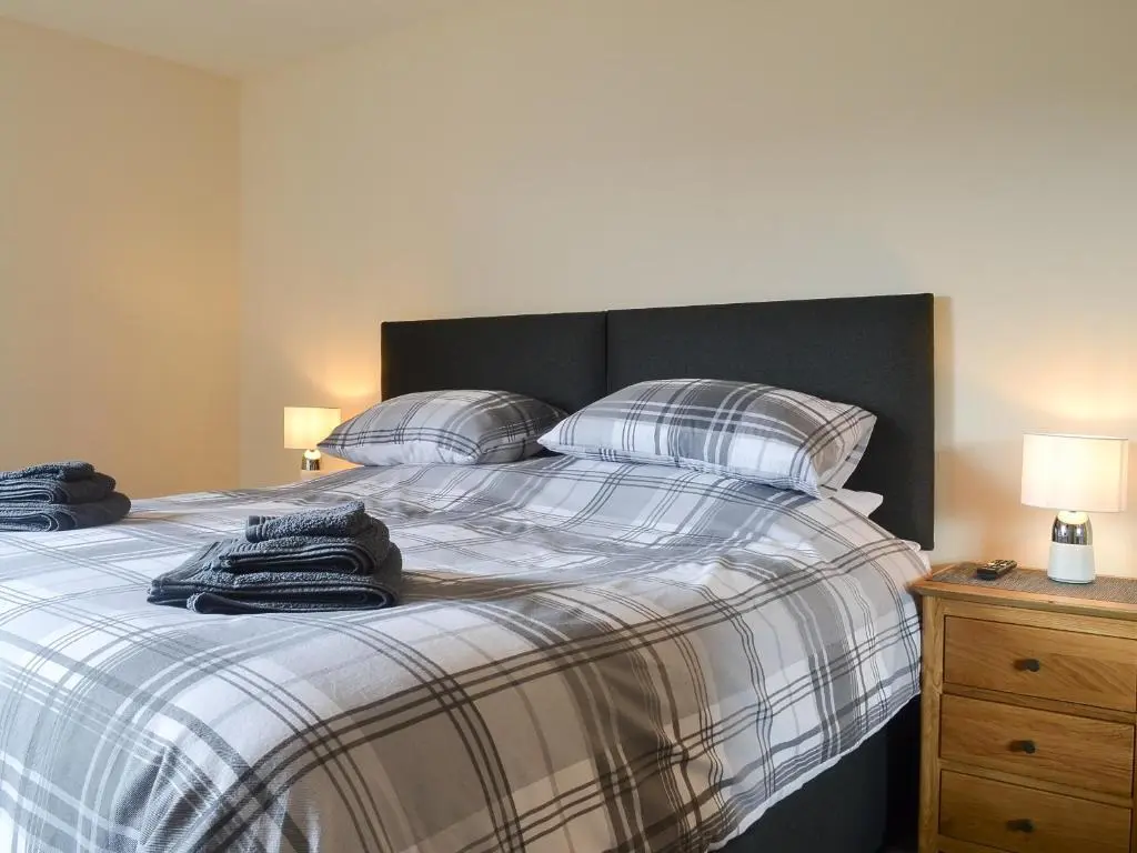 a bedroom with a bed with plaid sheets and pillows at Aurora in Lossiemouth