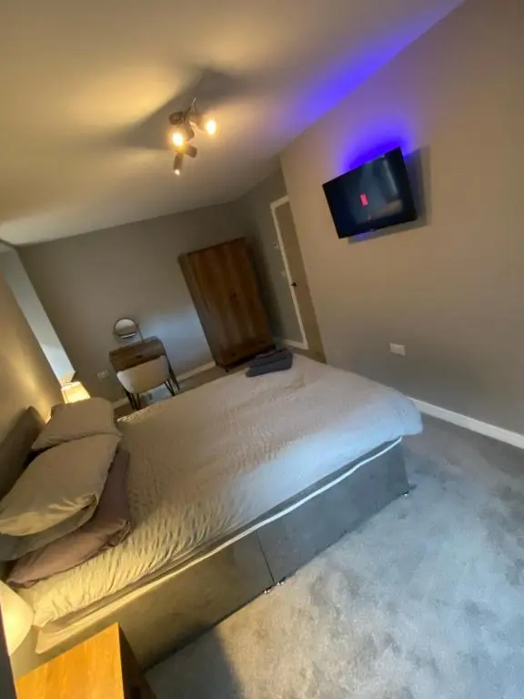 a bedroom with a bed and a tv on the wall at Town centre 3 bed luxury apartment in Wick