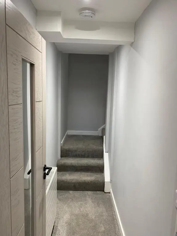 a hallway with stairs and a door with a stair case at Town centre 3 bed luxury apartment in Wick