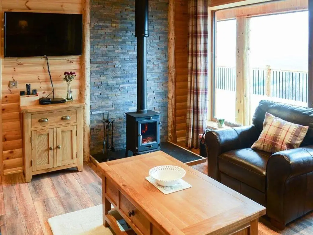 a living room with a wood stove and a couch at Red Kite & Osprey Lodges in Rhilochan