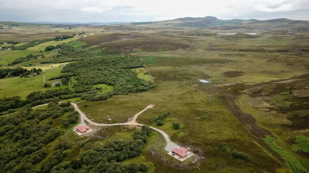 an aerial view of a field with houses and trees at Red Kite & Osprey Lodges in Rhilochan