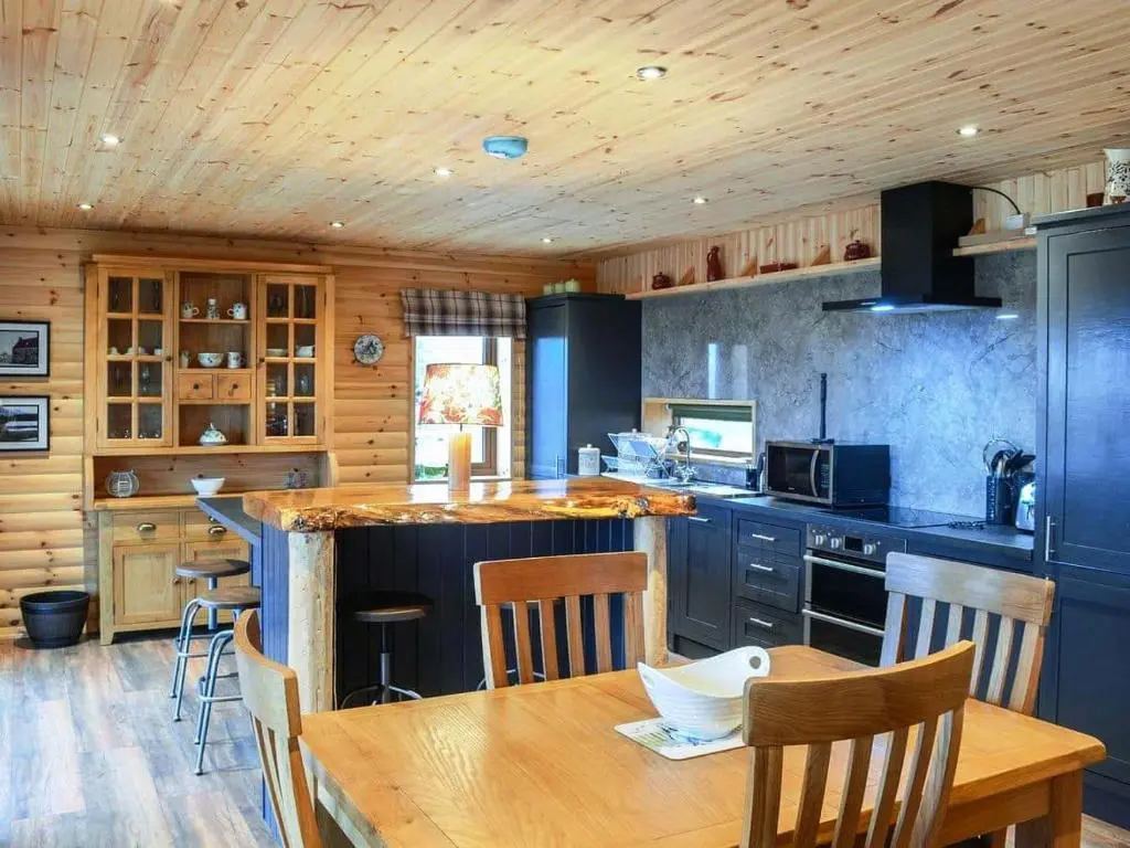 a kitchen with a wooden ceiling and a wooden table at Red Kite & Osprey Lodges in Rhilochan