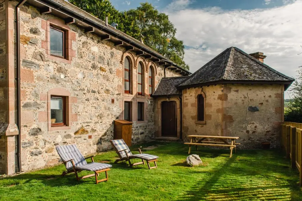 a yard with two chairs and a bench in front of a building at Beautiful Character House in Muir of Ord in Muir of Ord