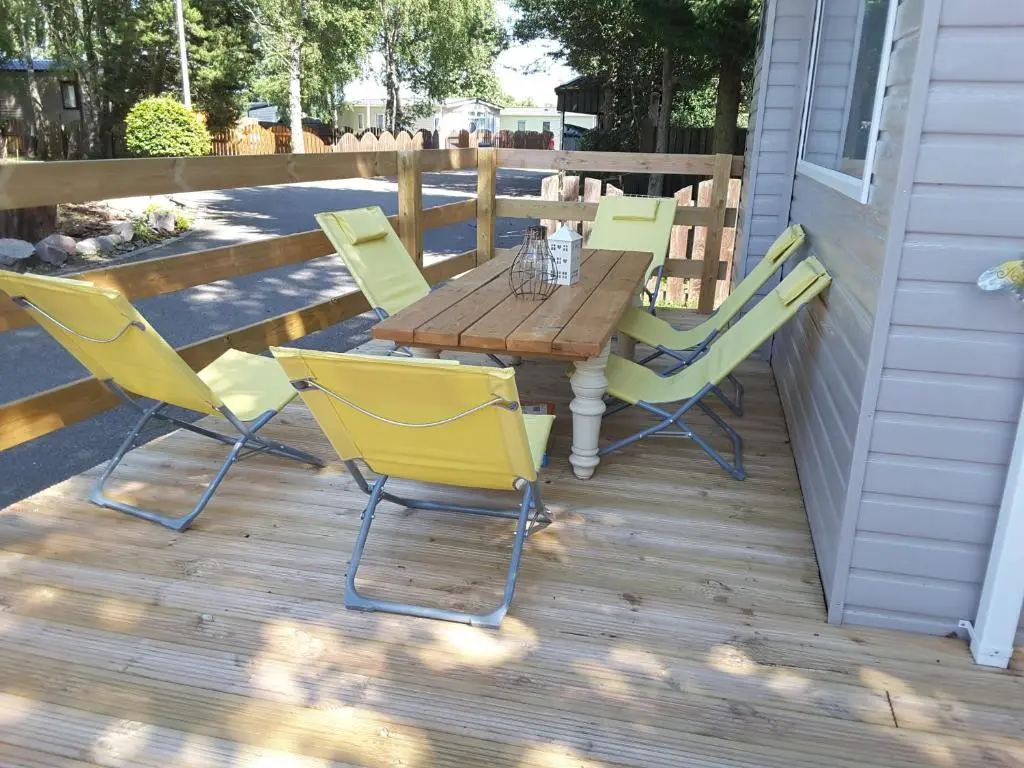 a wooden table and chairs on a deck at No 46 Coorie-in in Boat of Garten
