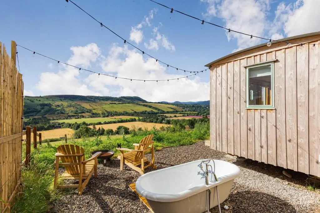 a bath tub sitting outside of a tiny house at Woodside Hut 3 - Uk36107 in Auchterneed