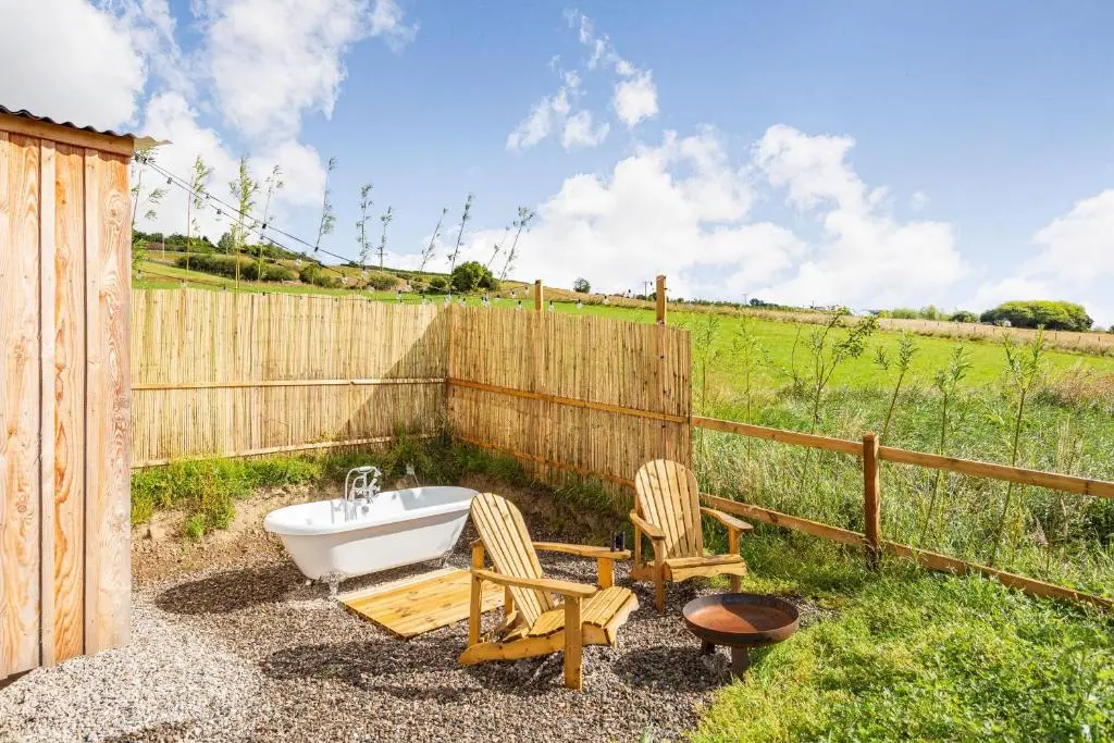 a bathroom with a tub and two chairs and a fence at Woodside Hut 3 - Uk36107 in Auchterneed