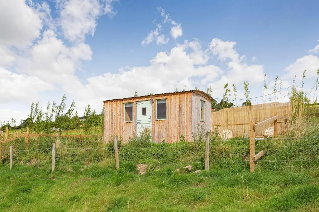 a small shack in a field with a fence at Woodside Hut 3 - Uk36107 in Auchterneed