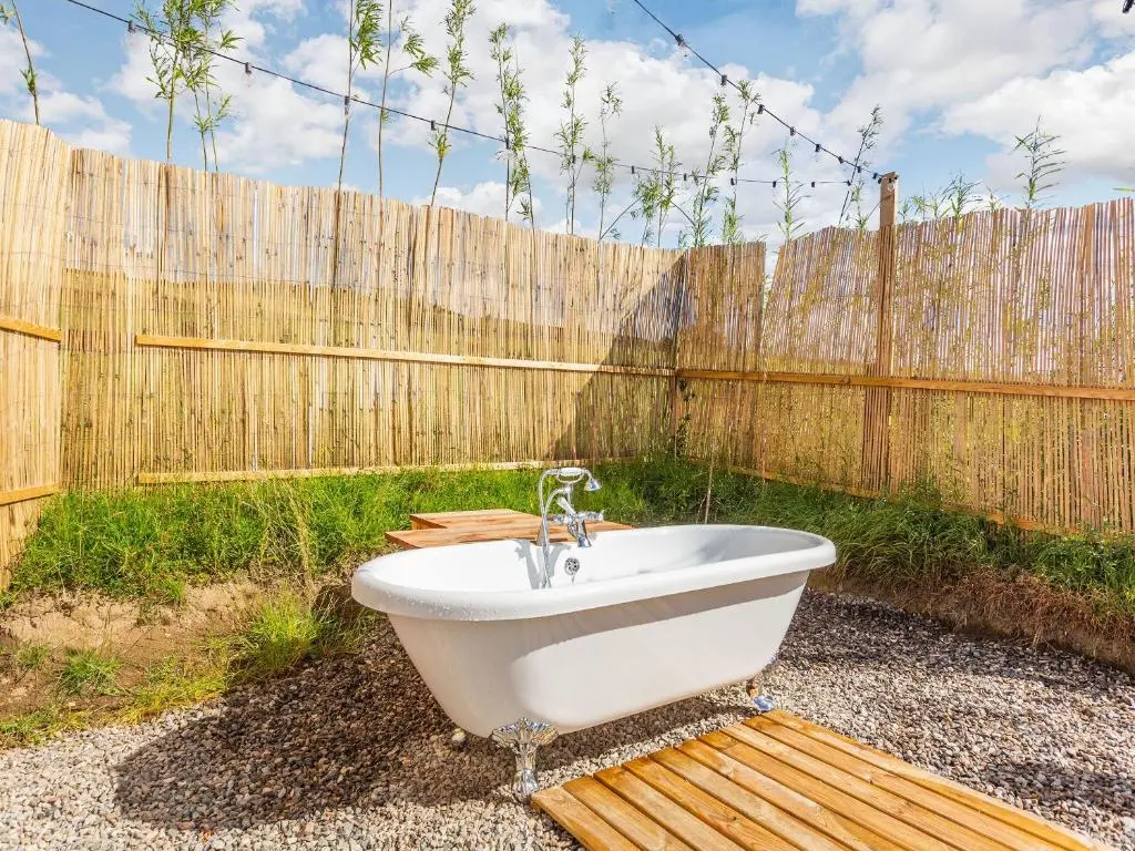 a bath tub sitting in a yard next to a fence at Woodside Hut 1 - Uk36105 in Auchterneed