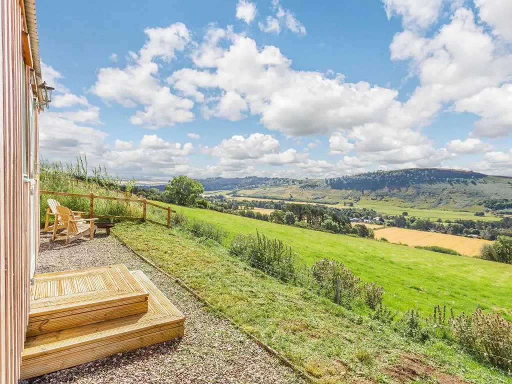 a garden with a bench and a view of a field at Woodside Hut 1 - Uk36105 in Auchterneed