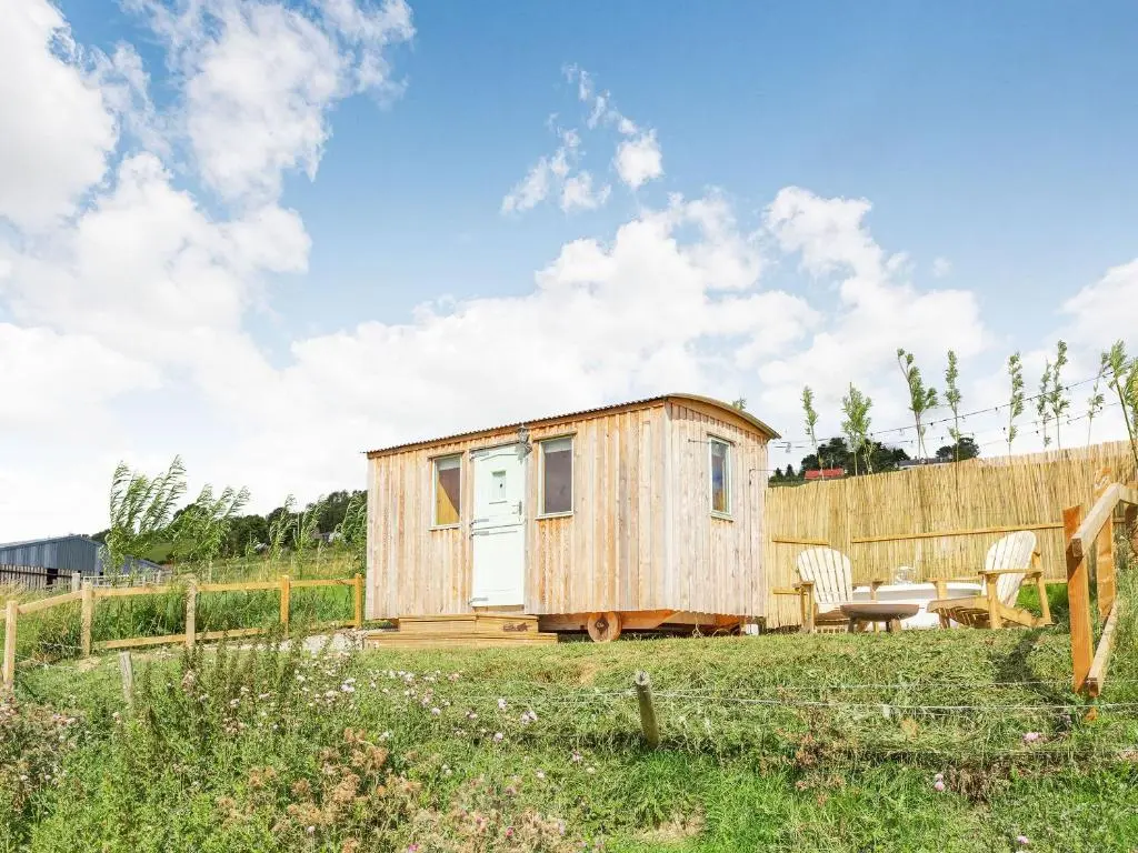 a tiny house in a field with a table and chairs at Woodside Hut 1 - Uk36105 in Auchterneed