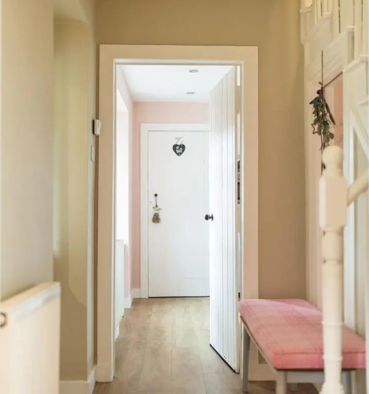 a hallway with a white door and a pink bench at Bramble Cottage in Turriff