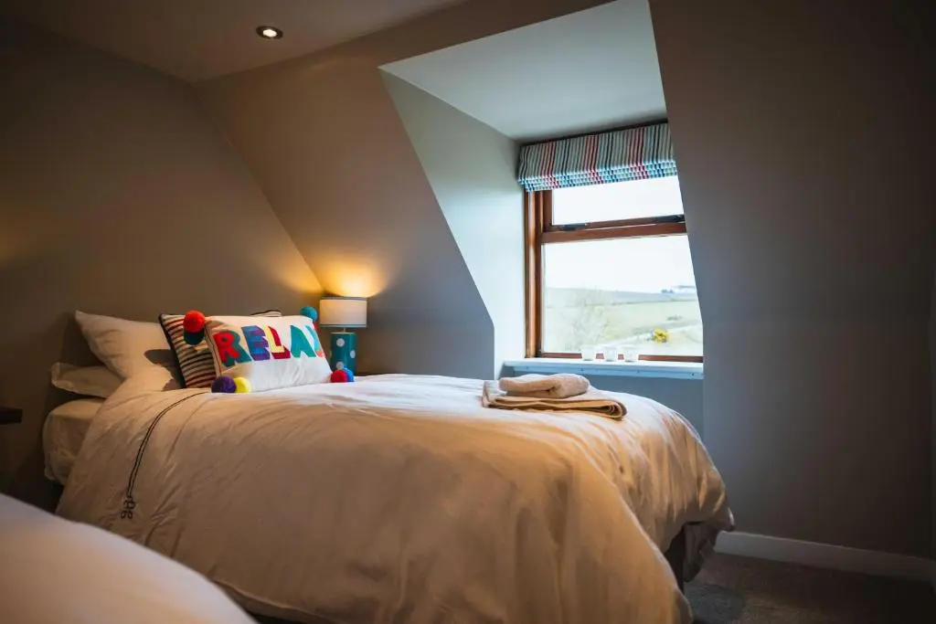 a bedroom with a large bed with a window at Bramble Cottage in Turriff