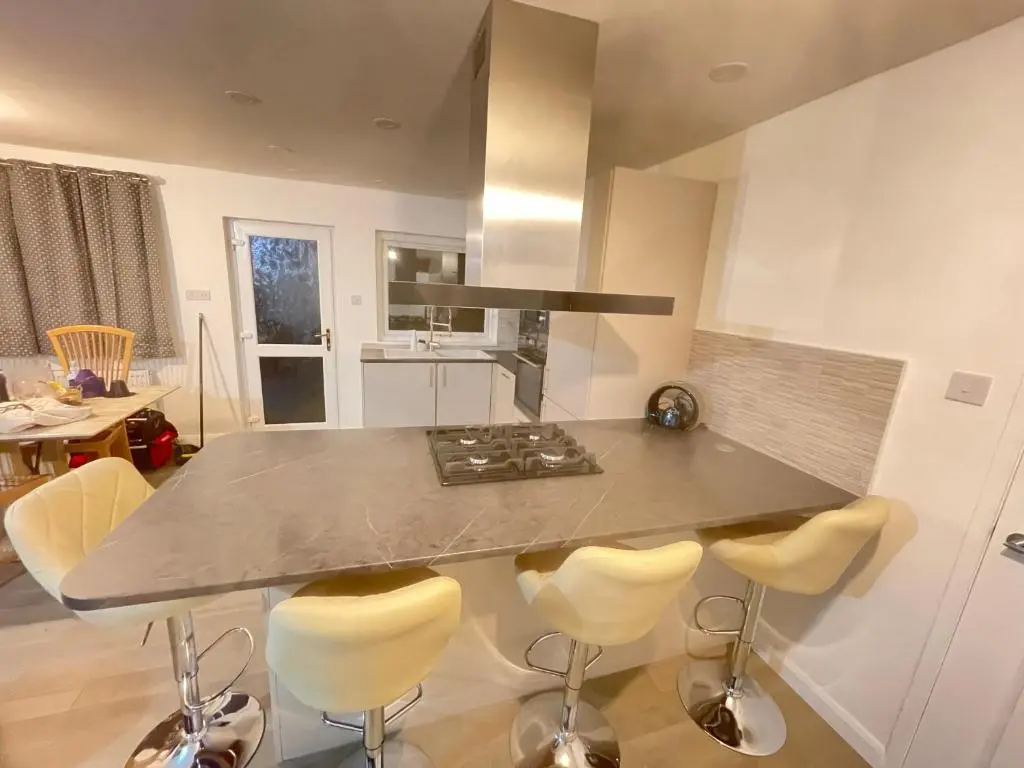a kitchen with a counter with a stove and chairs at Matara House Holiday Home in Inverness