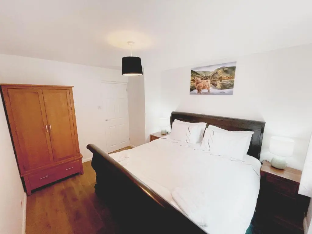a bedroom with a bed and a wooden cabinet at Matara House Holiday Home in Inverness