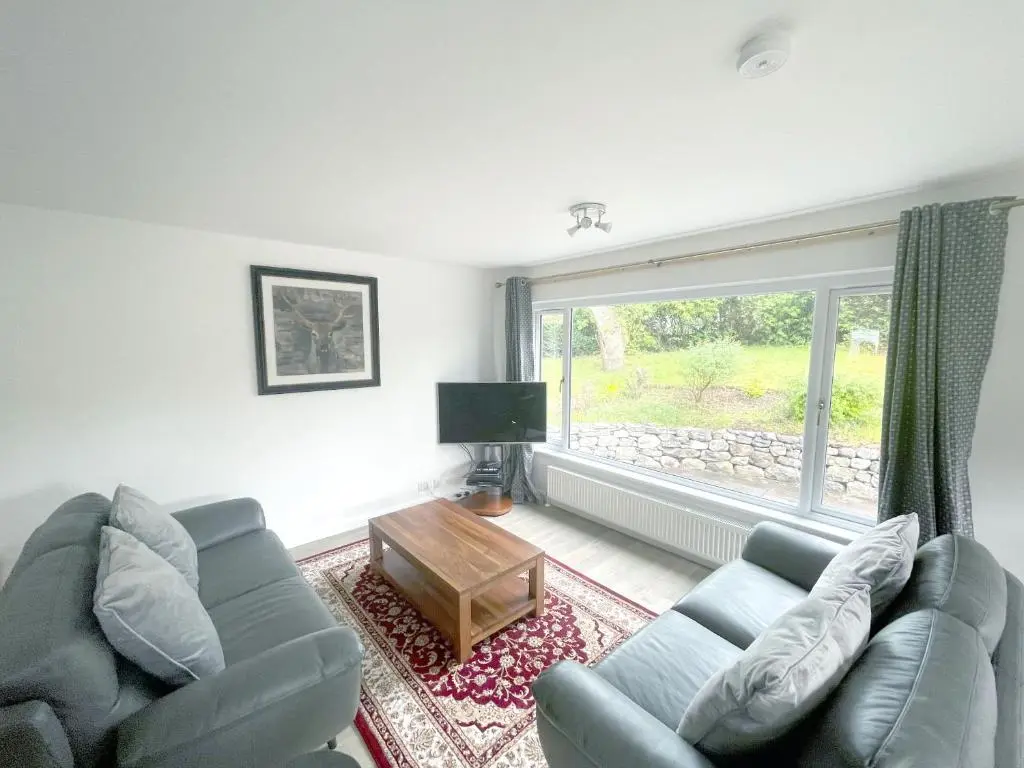 a living room with a couch and a large window at Matara House Holiday Home in Inverness