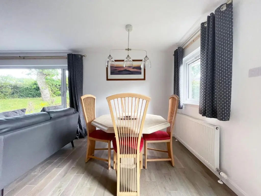 a dining room with a table and chairs and a window at Matara House Holiday Home in Inverness