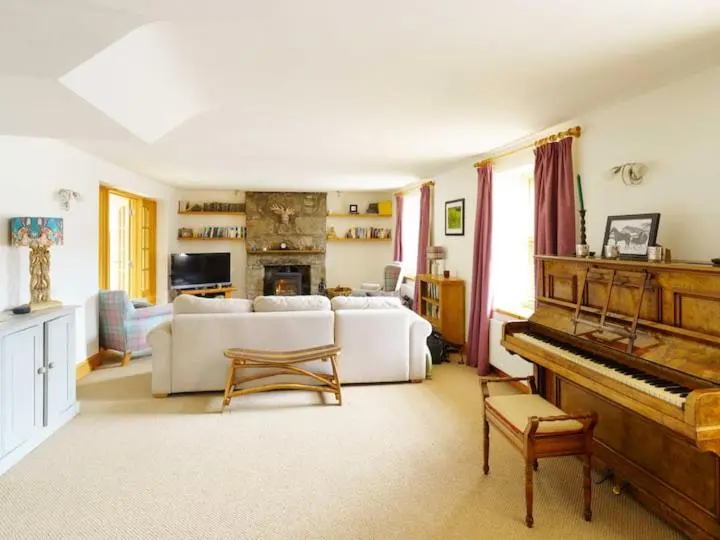 a living room with a couch and a piano at Milne's Brae, cosy, comfortable and centrally located in beautiful Braemar in Braemar