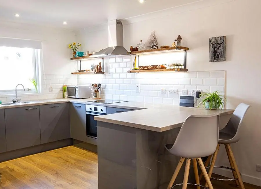 a kitchen with a counter and two chairs in it at Croftwood Cottage in Boat of Garten