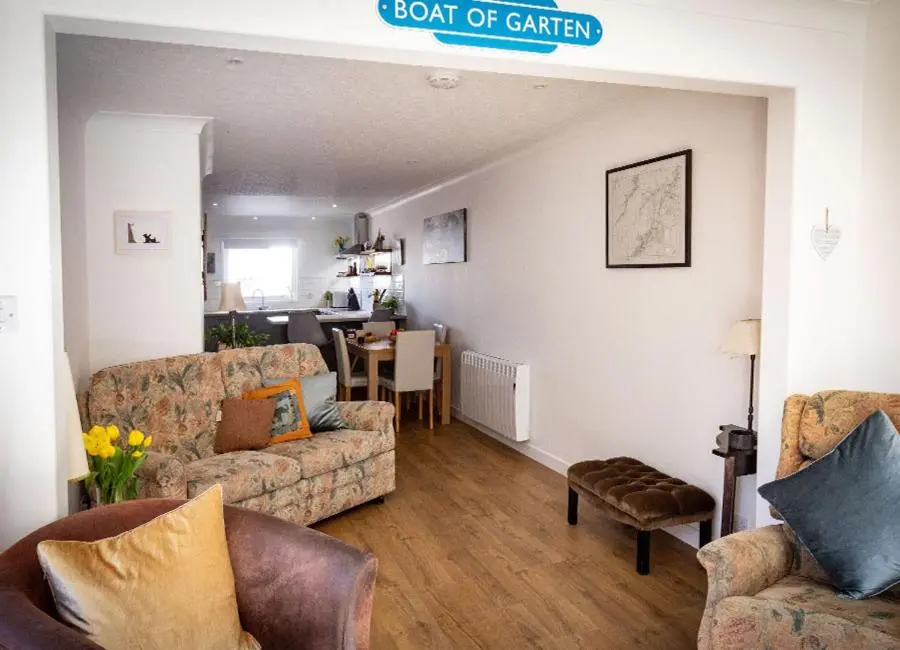 a living room with two couches and a table at Croftwood Cottage in Boat of Garten