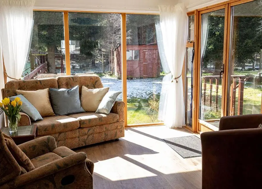 a living room with a couch and a sliding glass door at Croftwood Cottage in Boat of Garten