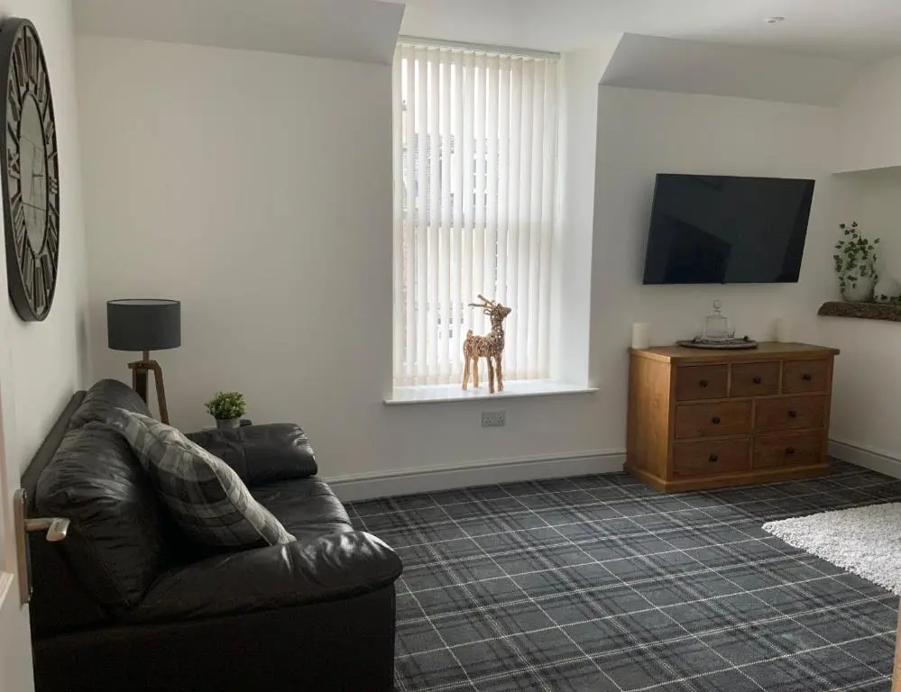 a living room with a couch and a toy giraffe in the window at Deeside Snugs Apartments in Kincardine O\u02bcNeil