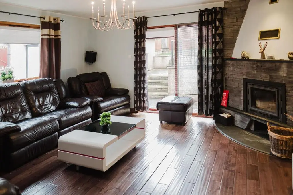 a living room with a leather couch and a fireplace at Willa , Cosy house in Inverness in Inverness