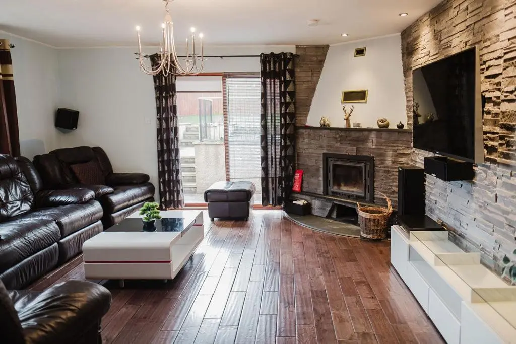 a living room with a leather couch and a fireplace at Willa , Cosy house in Inverness in Inverness