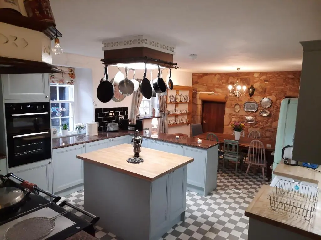 a kitchen with white cabinets and a counter top at Lickleyhead Castle in Insch