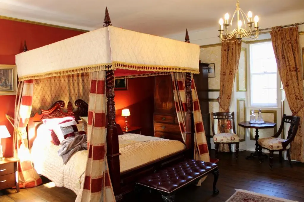 a bedroom with a canopy bed and red walls at Lickleyhead Castle in Insch