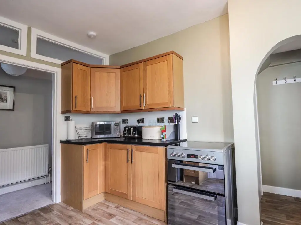a kitchen with wooden cabinets and stainless steel appliances at 62 Society Street in Nairn