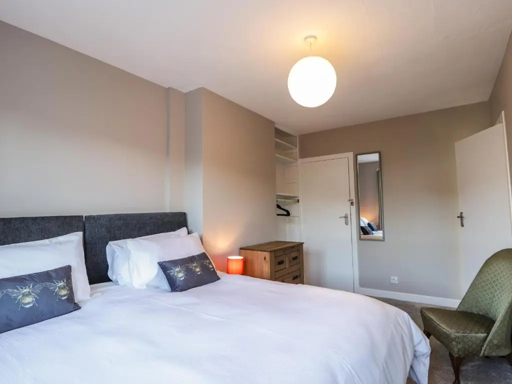 a bedroom with a large white bed and a chair at 62 Society Street in Nairn