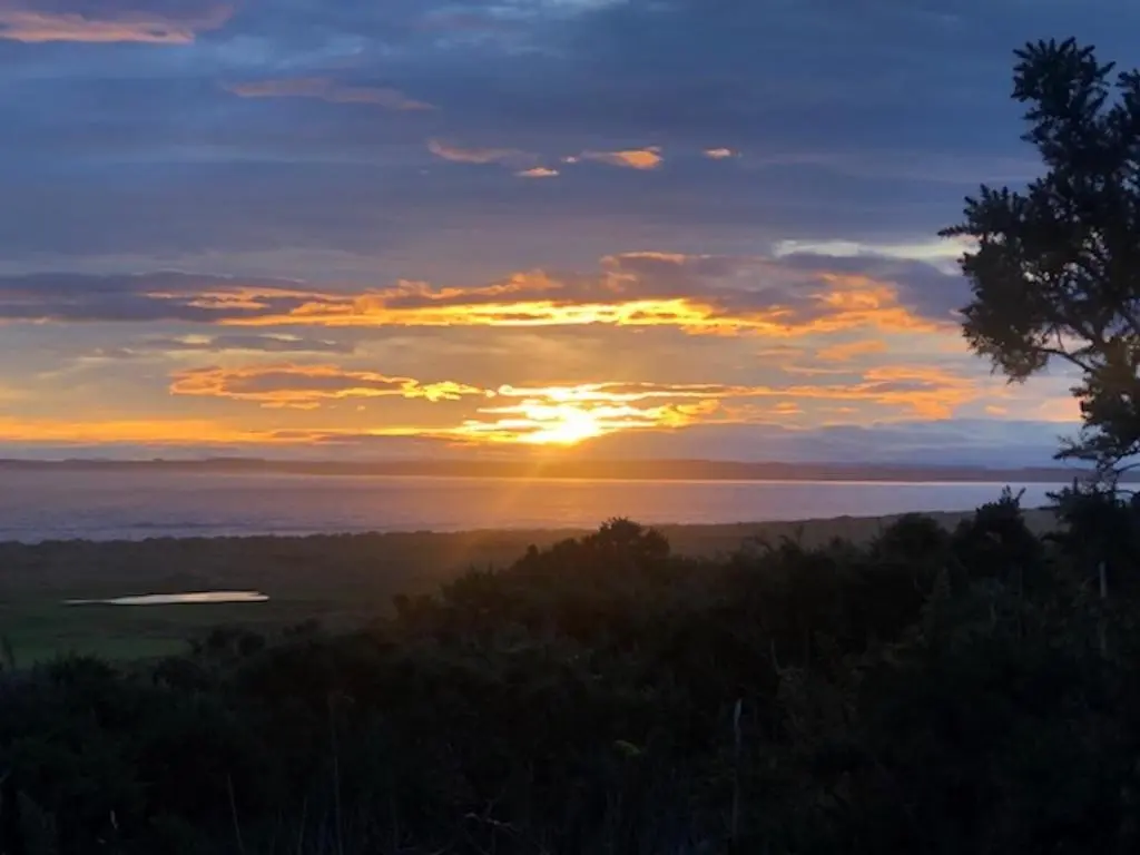 a sunset over the water with the sun setting at Balloan Steading West in Dornoch