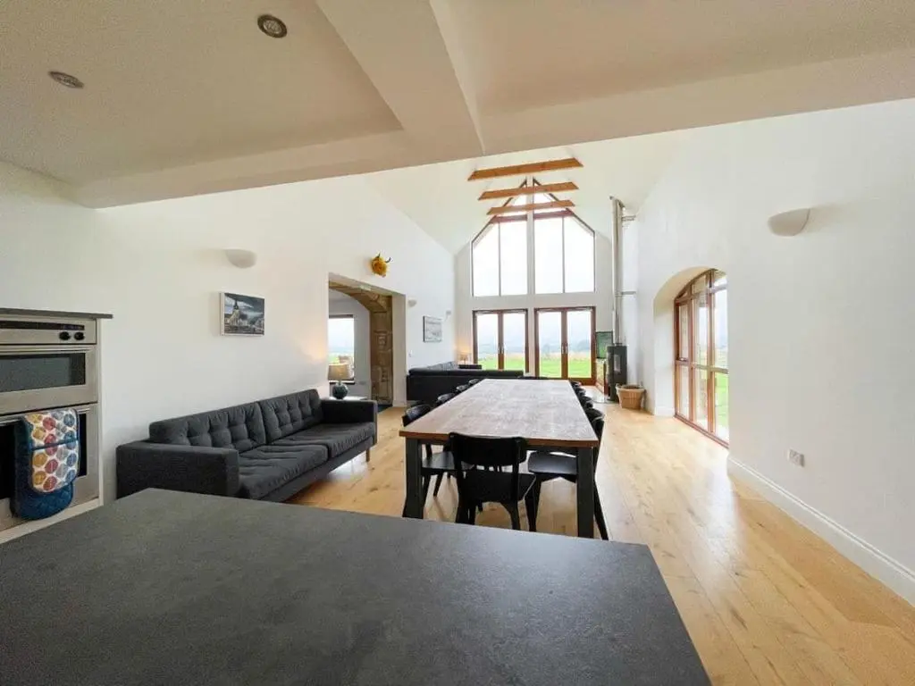 a living room with a table and a couch at Balloan Steading West in Dornoch