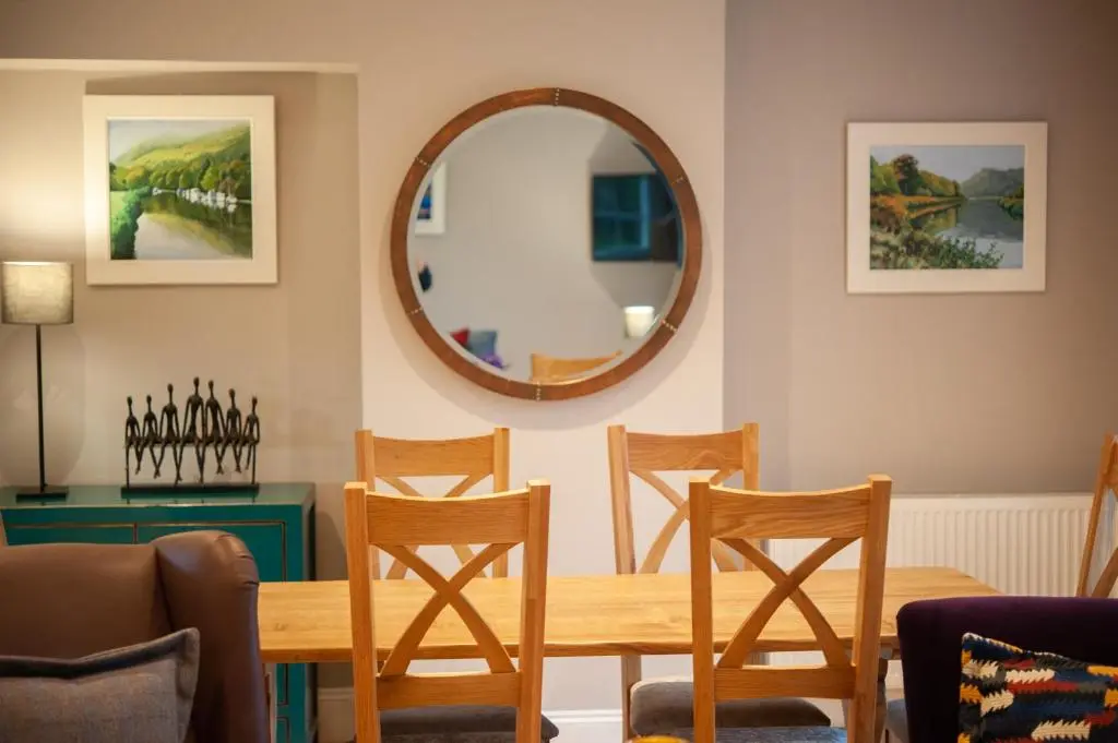 a dining room with a table and chairs and a mirror at Parkside, The Loch Ness Cottage Collection in Inverness