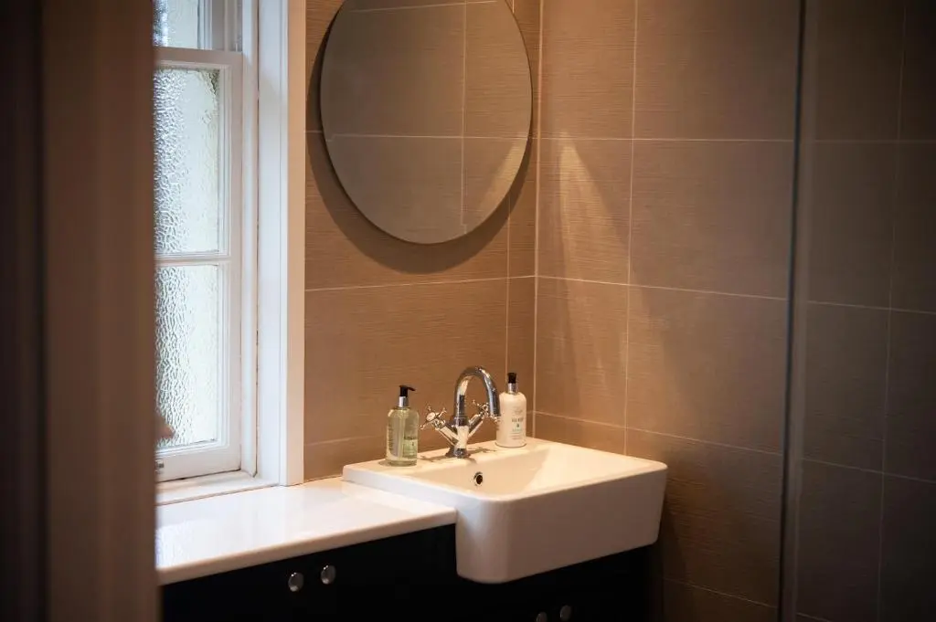 a bathroom with a sink and a mirror at Parkside, The Loch Ness Cottage Collection in Inverness