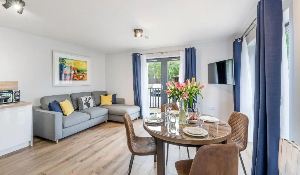 a living room with a table and chairs and a couch at High Range Holiday Apartments in Aviemore