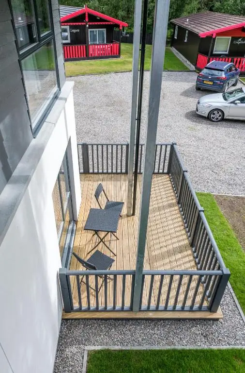 two chairs sitting on a deck next to a building at High Range Holiday Apartments in Aviemore