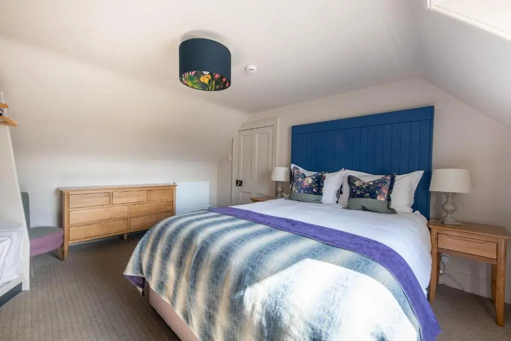 a bedroom with a large bed with a blue headboard at The Cottage, The Loch Ness Cottage Collection in Inverness