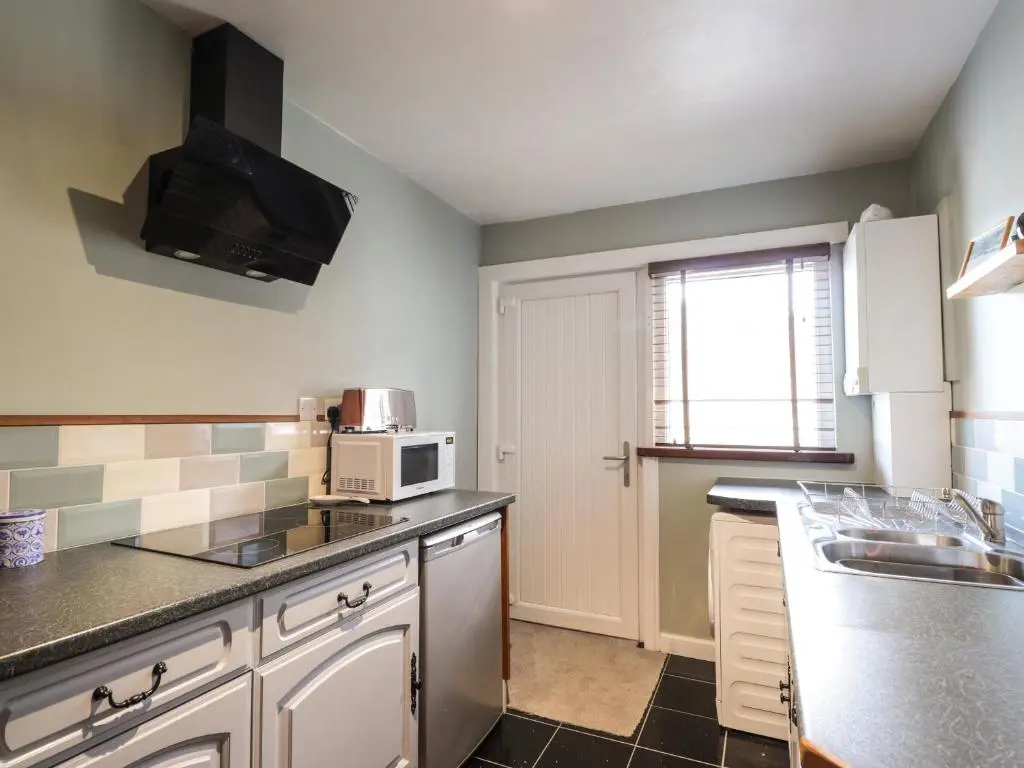 a kitchen with a sink and a microwave at Griffin Cottage in Nairn