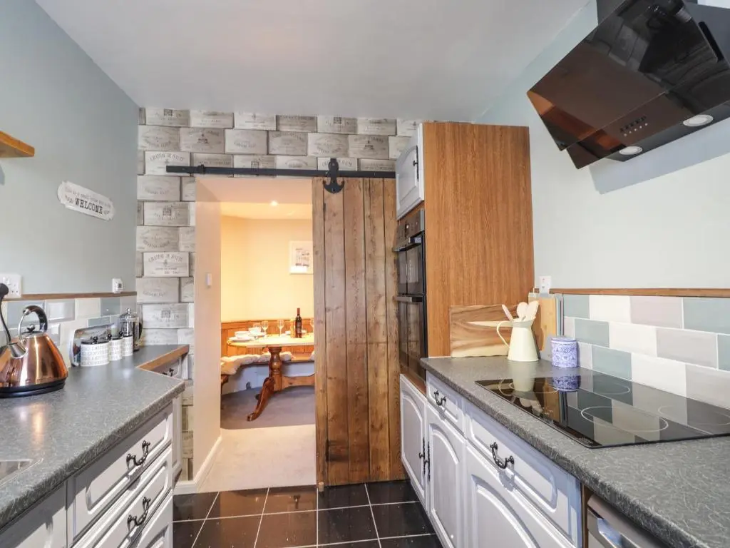 a kitchen with a door leading to a dining room at Griffin Cottage in Nairn