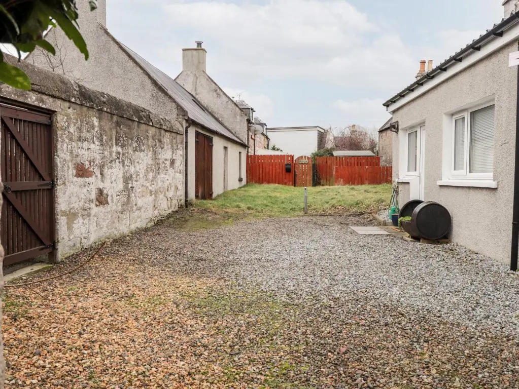 an alleyway between two houses with a fence at Griffin Cottage in Nairn