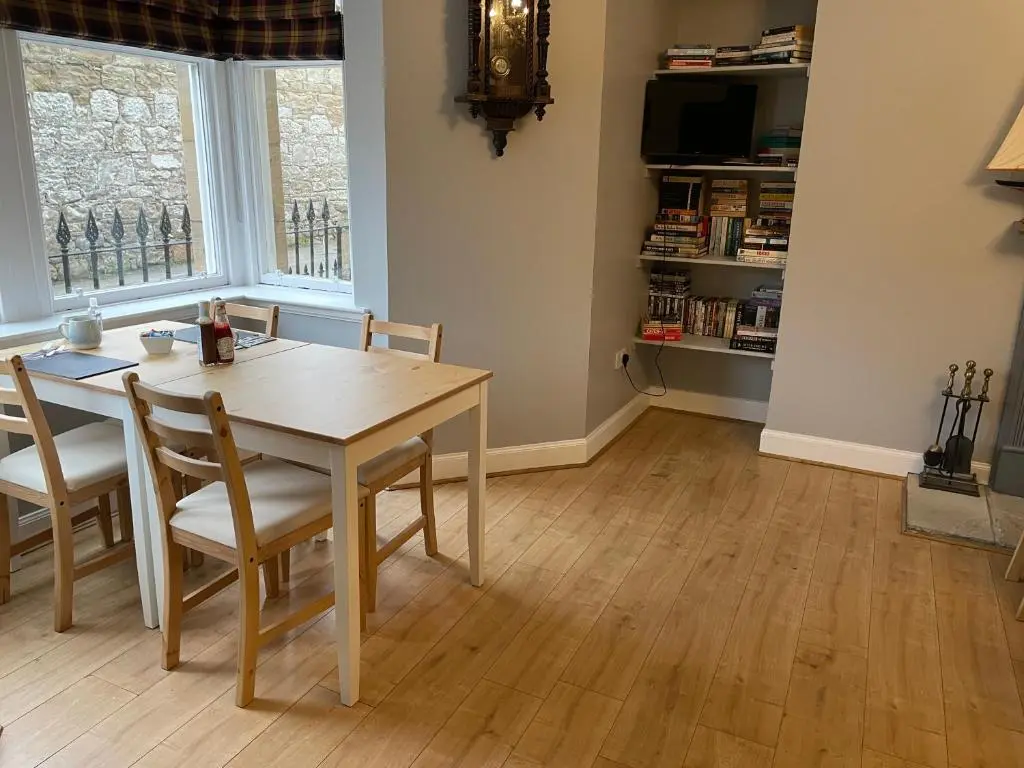 a dining room with a wooden table and chairs at Shandwick House in Tain