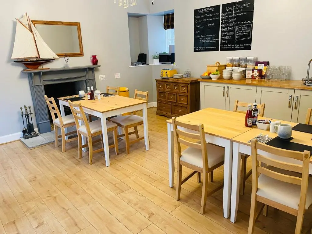 a kitchen with wooden tables and chairs and a counter at Shandwick House in Tain