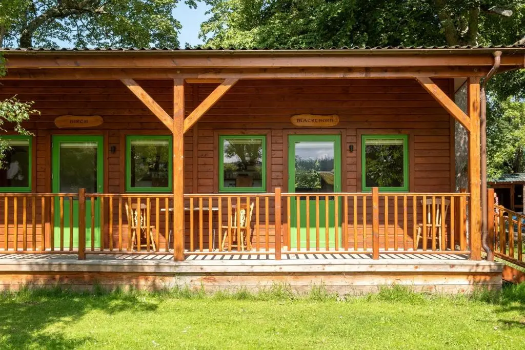 a log cabin with chairs on the porch at Marcassie Farm Lodges - Blackthorn Studio in Forres